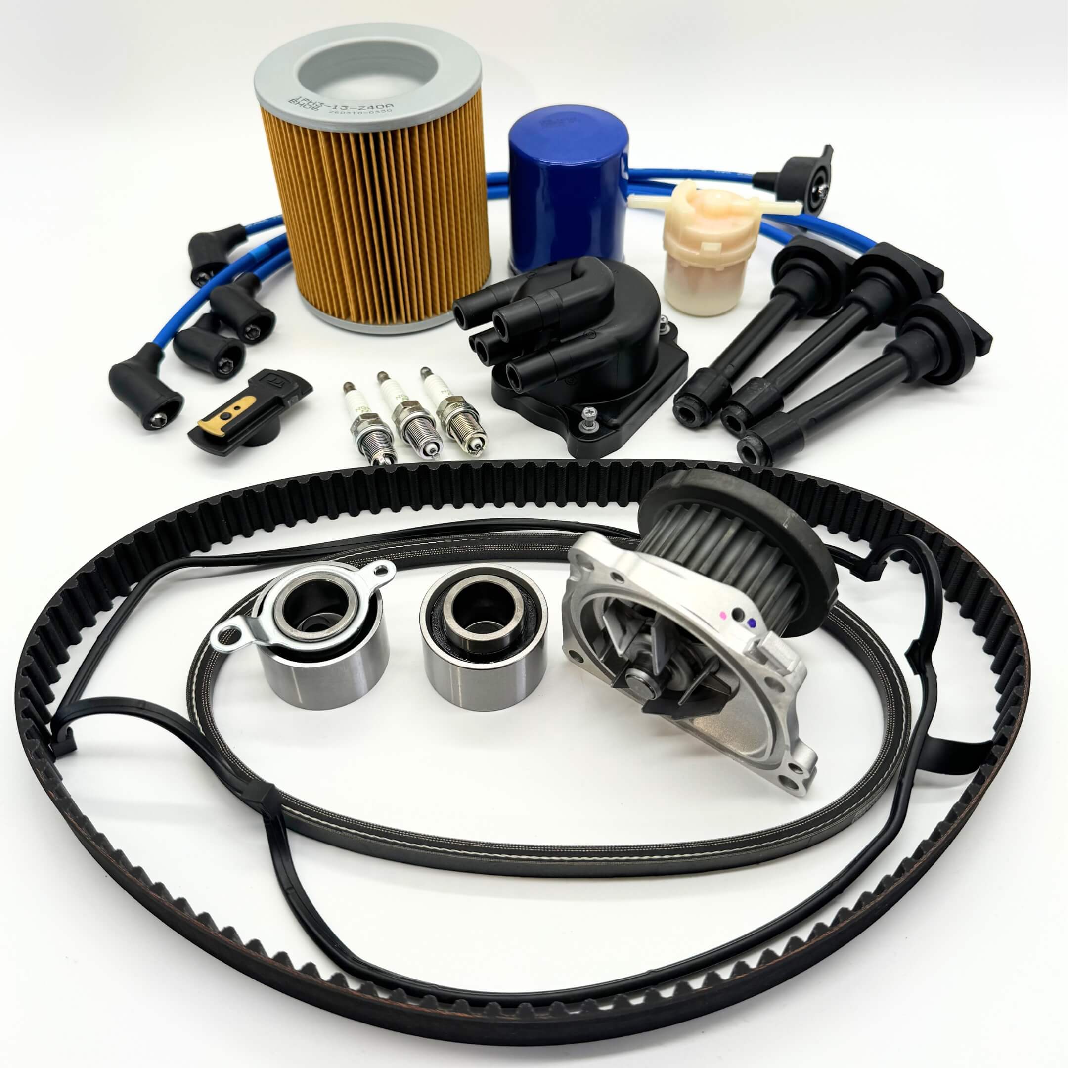 16-piece Mega Timing Belt and Tune-Up Kit for Honda Acty HH3/HH4 1990-1999, comprising an air filter, fuel filter, oil filter, distributor cap and rotor, spark plugs with wires, timing and alternator belt set, and head cover gasket, presented neatly on a white background, exclusively available with free shipping from Oiwa Garage.