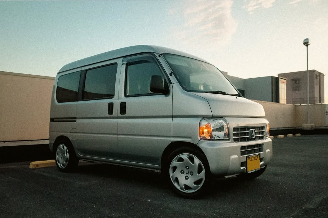 Silver Honda Acty Van HH5, HH6 (1999-2009) parked in an urban setting, highlighting its compact design, practical sliding doors, and suitability for city driving.








